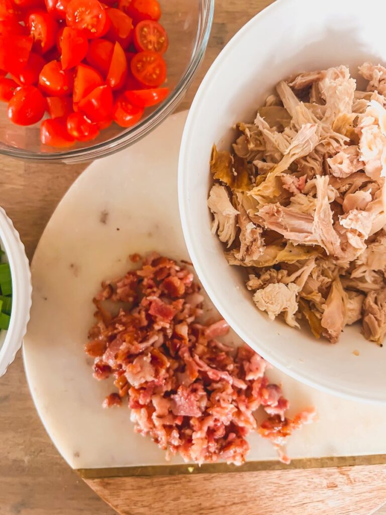 Chicken, tomatoes, peppers, and bacon in serving bowls