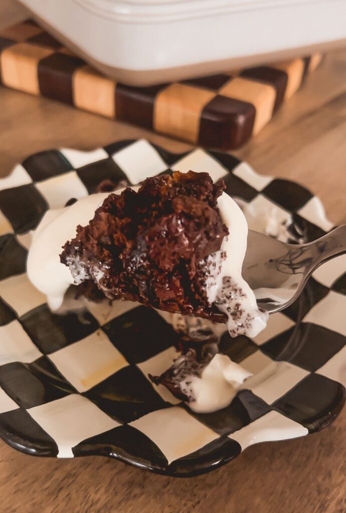 Close-up of chocolate cake covered with whipped cream on a black-and-white checkered plate