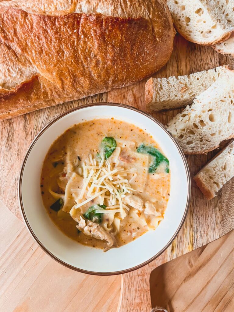 White chicken lasagna soup in a bowl with bread