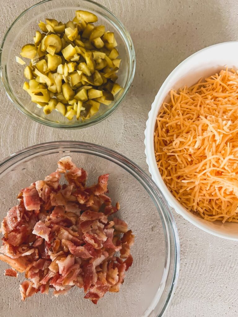Bowls of shredded cheese, bacon, and veggies