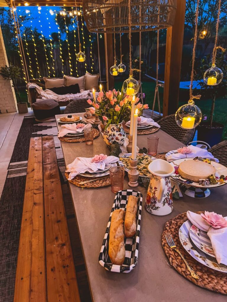 Curtain of twinkle lights illuminate a back porch swing in front of a garden party