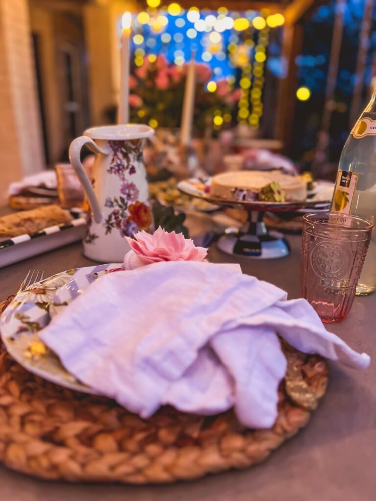 White napkin tied with a floral napkin ring in front of a floral pitcher