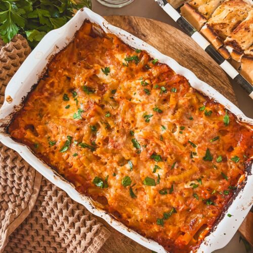 Easy no boil baked ziti on a wooden cutting board with a linen.