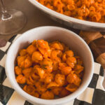 Pasta shells in a white bowl layered over a black-and-white checkered plate