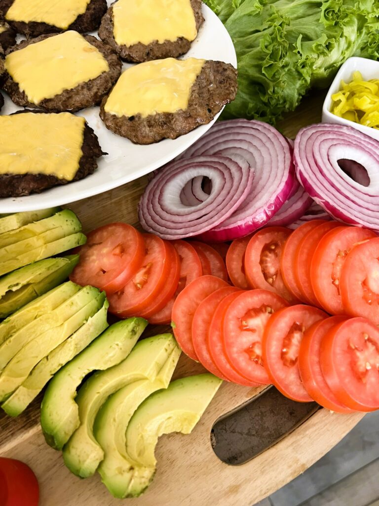 Close-up of Build-Your-Own Burger Bar toppings with tomatoes, onions, and avocado