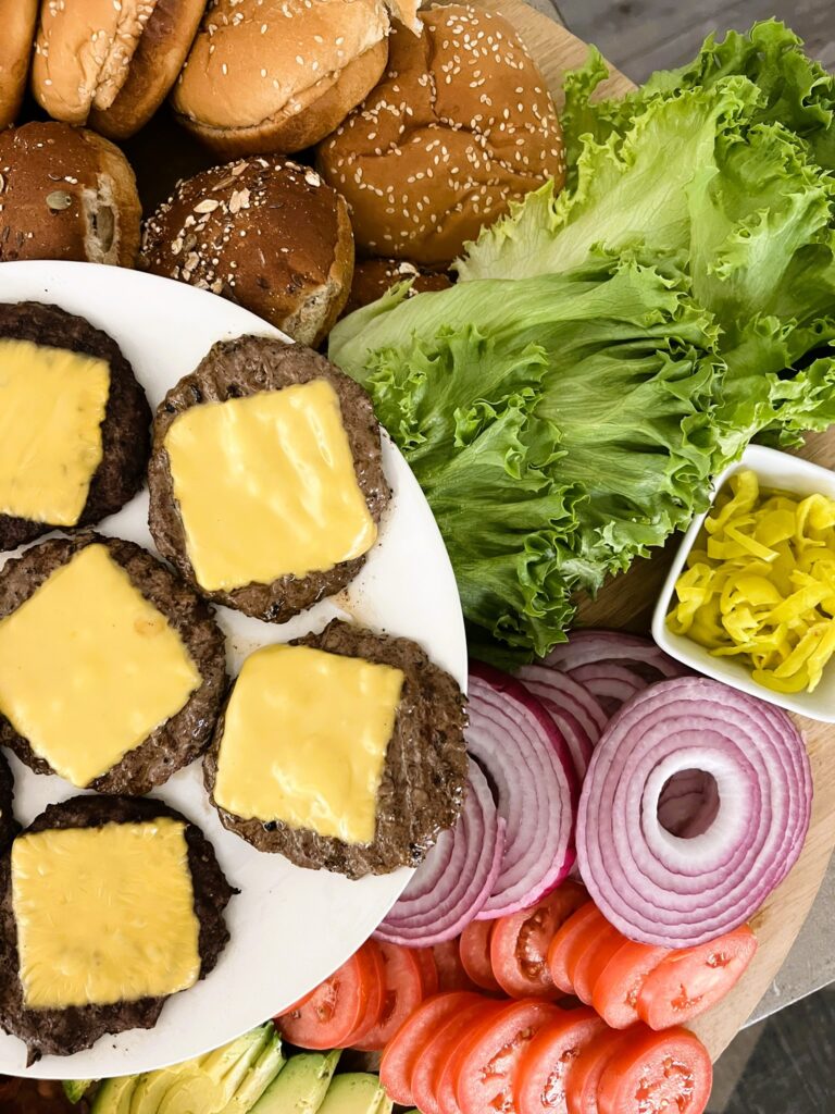 Cheeseburger on a plate surrounded by toppings