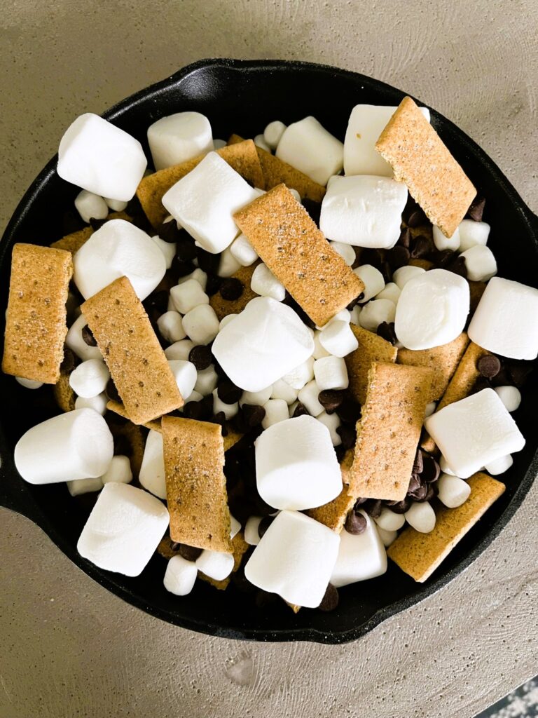 Marshmallows, graham crackers, and chocolate chips layered in a skillet