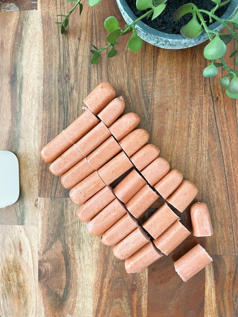 Hot dogs cut in half on a wooden serving board