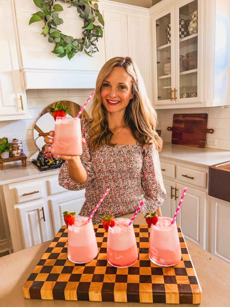 Leanna holding a strawberry champagne float in a sunny white kitchen