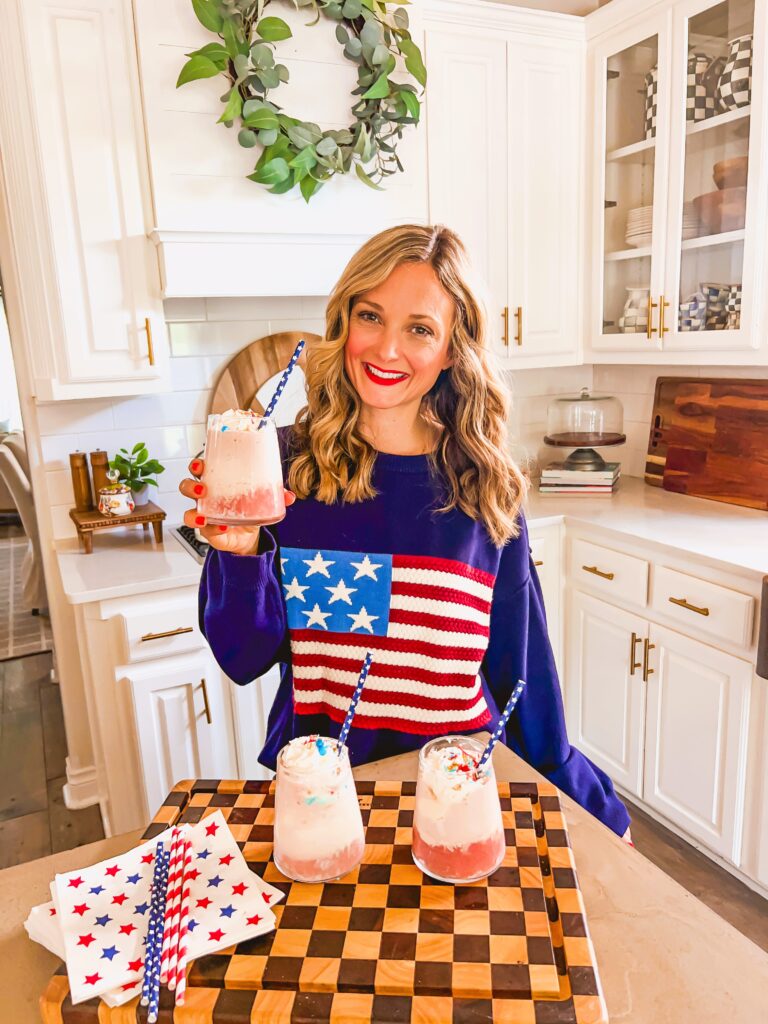 Leanna holding a glass with a Red Wine Float in a sunny white kitchen