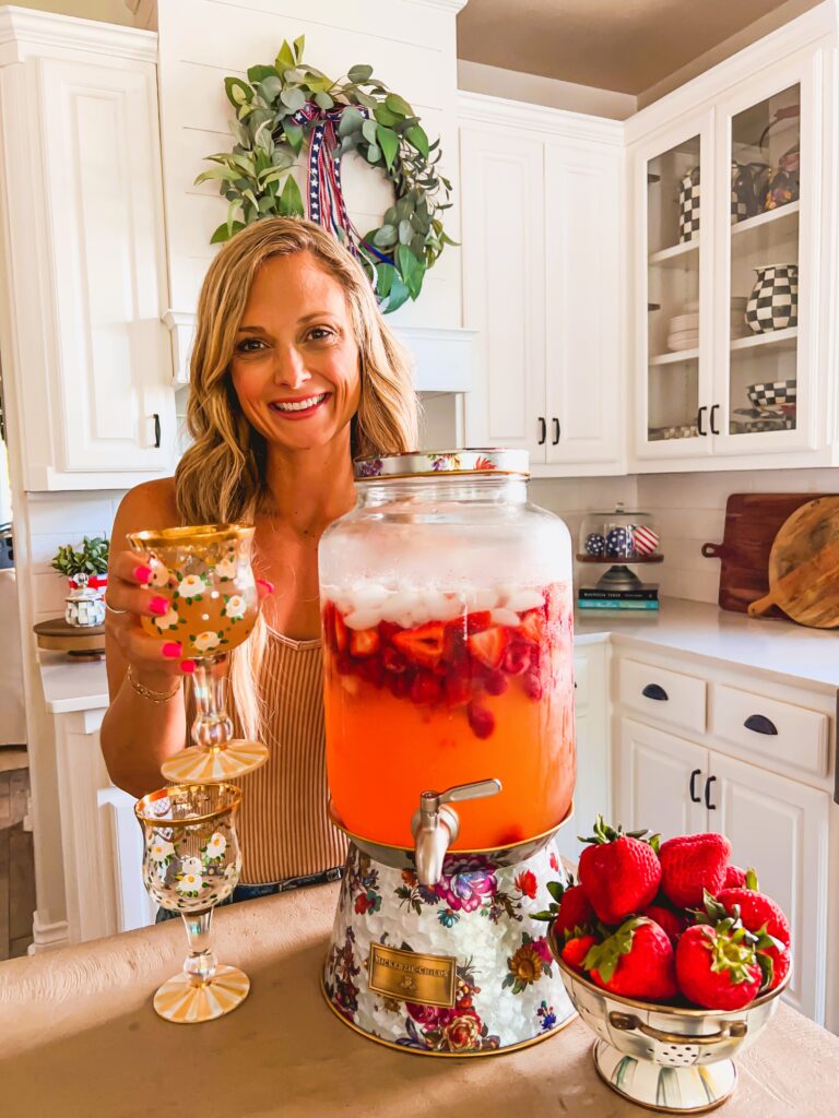 Leanna holding a glass of Strawberry Lemonade Sangria in a sunny white kitchen