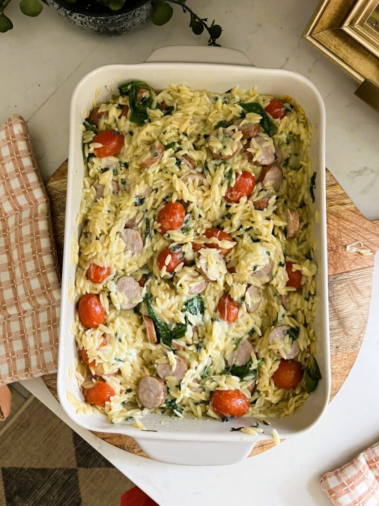spinach and artichoke orzo bake in a white pan