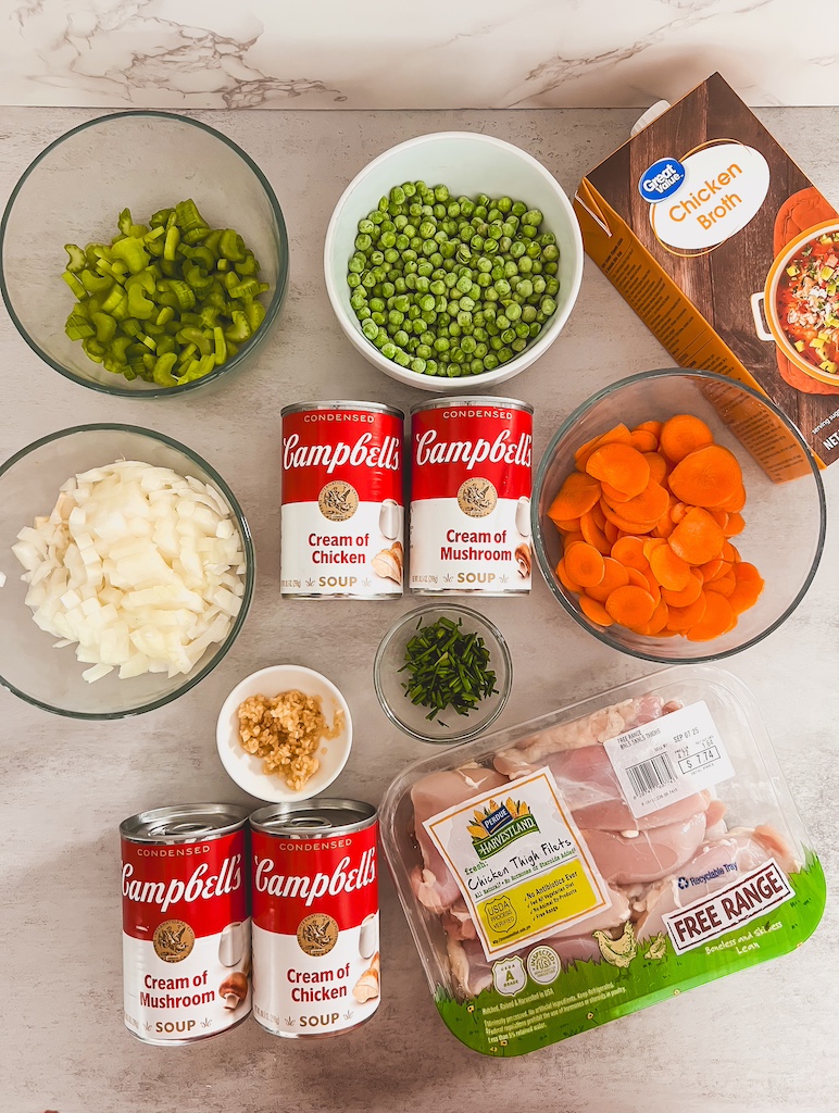 All ingredients for crockpot chicken and dumpling soup laid out, including chicken, veggies, soups,
