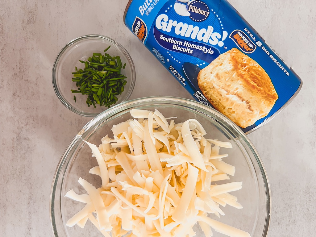 All ingredients for crockpot chicken and dumpling soup laid out, including biscuits, cheese and parsley
