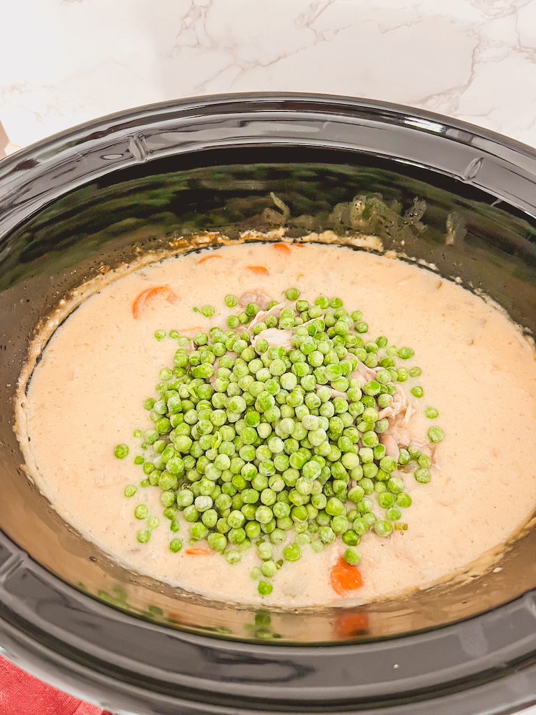 crockpot with peas being added to soup