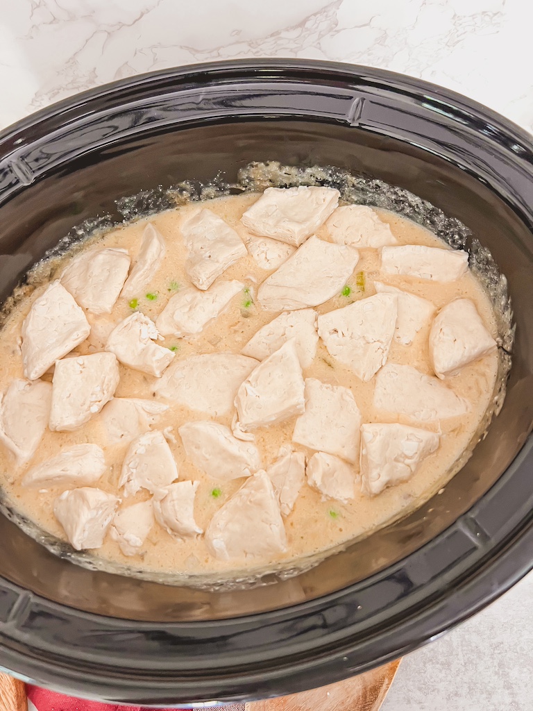 Biscuit dough pieces layered on top of the soup in a slow cooker