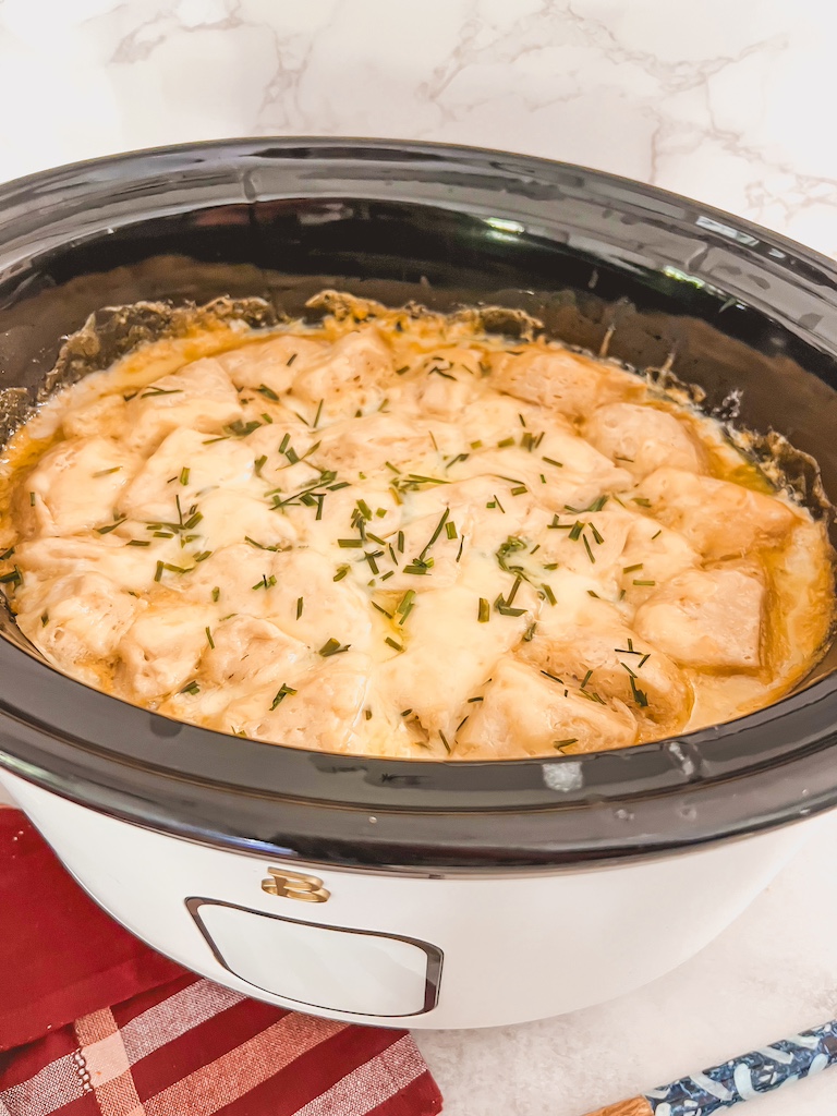 Crockpot chicken and dumpling soup finished with fluffy biscuits and melted cheese.