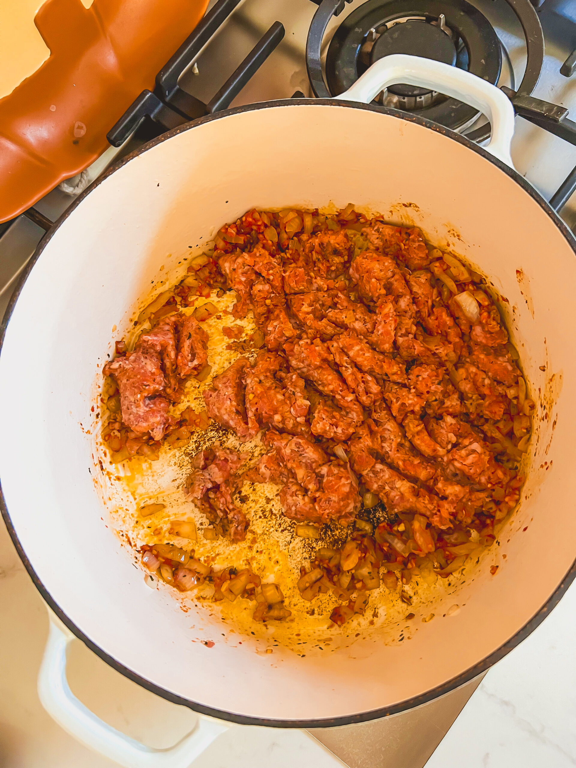 Italian sausage browning in a Dutch oven for ravioli soup base