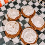 Plate of pumpkin cookies surrounded by fall leaves and cozy autumn decor.