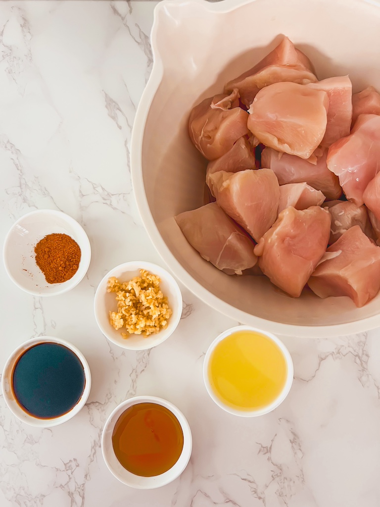 Overhead photo of ingredients for bang bang chicken skewers including chicken, spices, and sauce