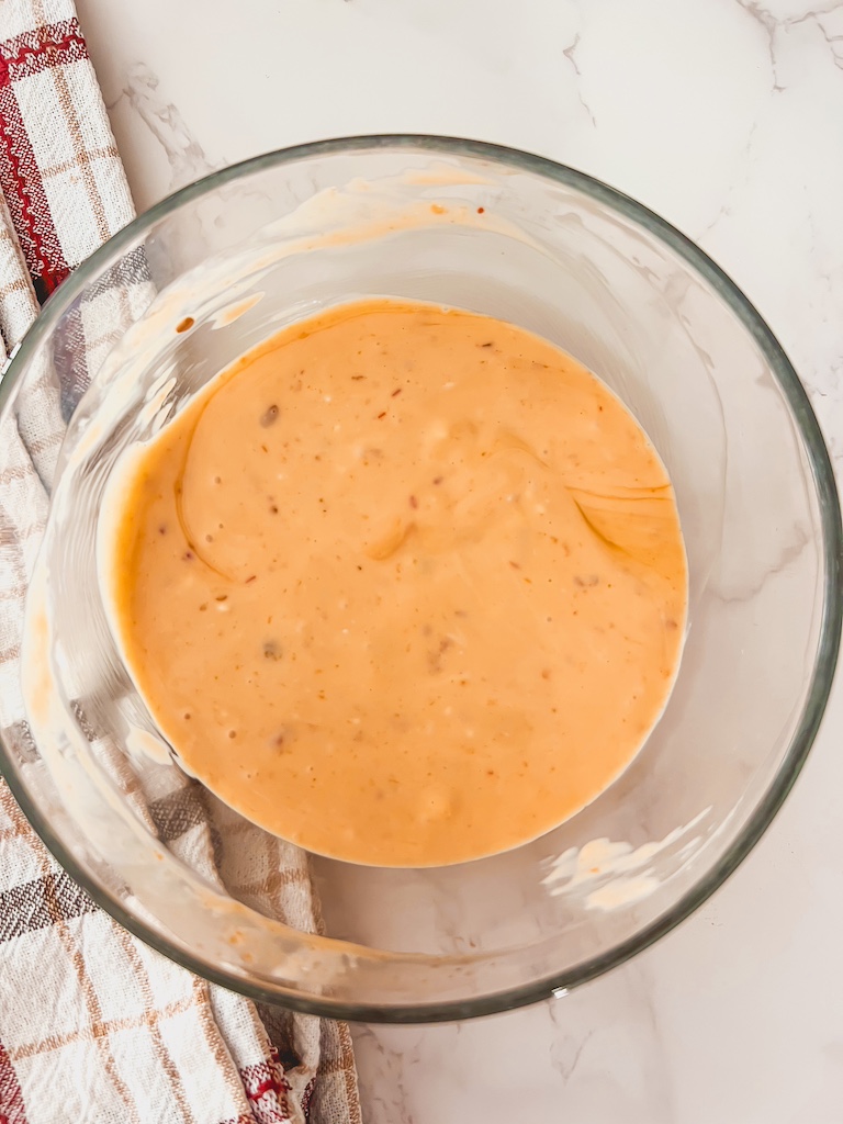 Whisking mayonnaise, sweet chili sauce, sriracha, and honey in a bowl to make bang bang sauce