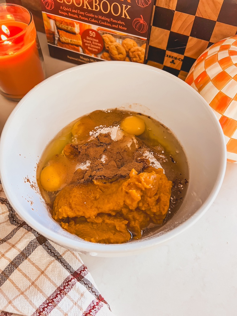 Pumpkin spice cake batter mixed with pumpkin purée, eggs, and oil in a glass bowl.