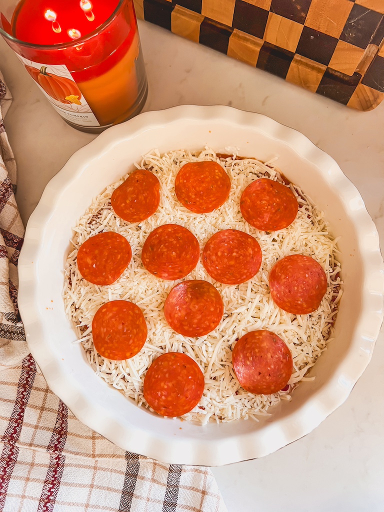 adding pepperoni to the pizza dip for easy game day appetizer