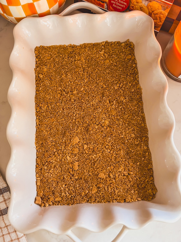 pressing buttery graham cracker crust into 9x13 dish