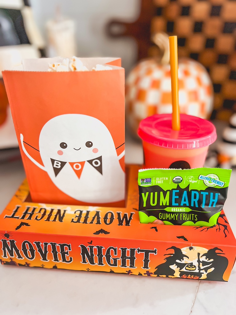 Halloween movie night tray with popcorn, candy, and festive Halloween cup.