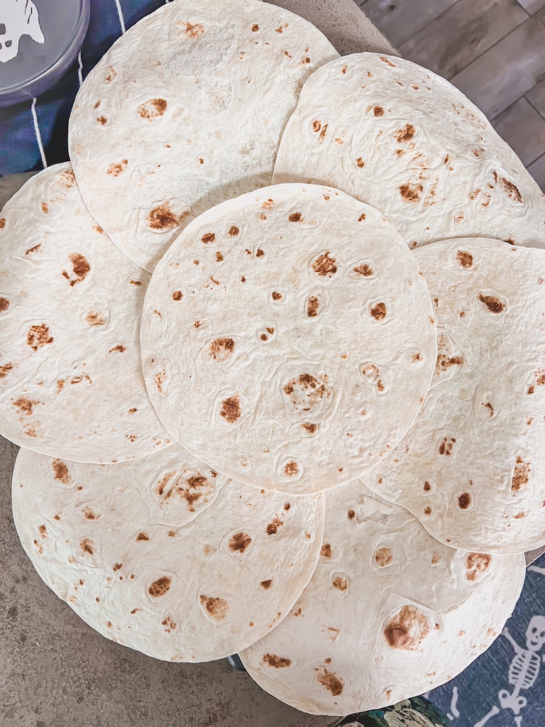 Overlapping flour tortillas around a pizza pan to form crust for jack-o-lantern quesadilla