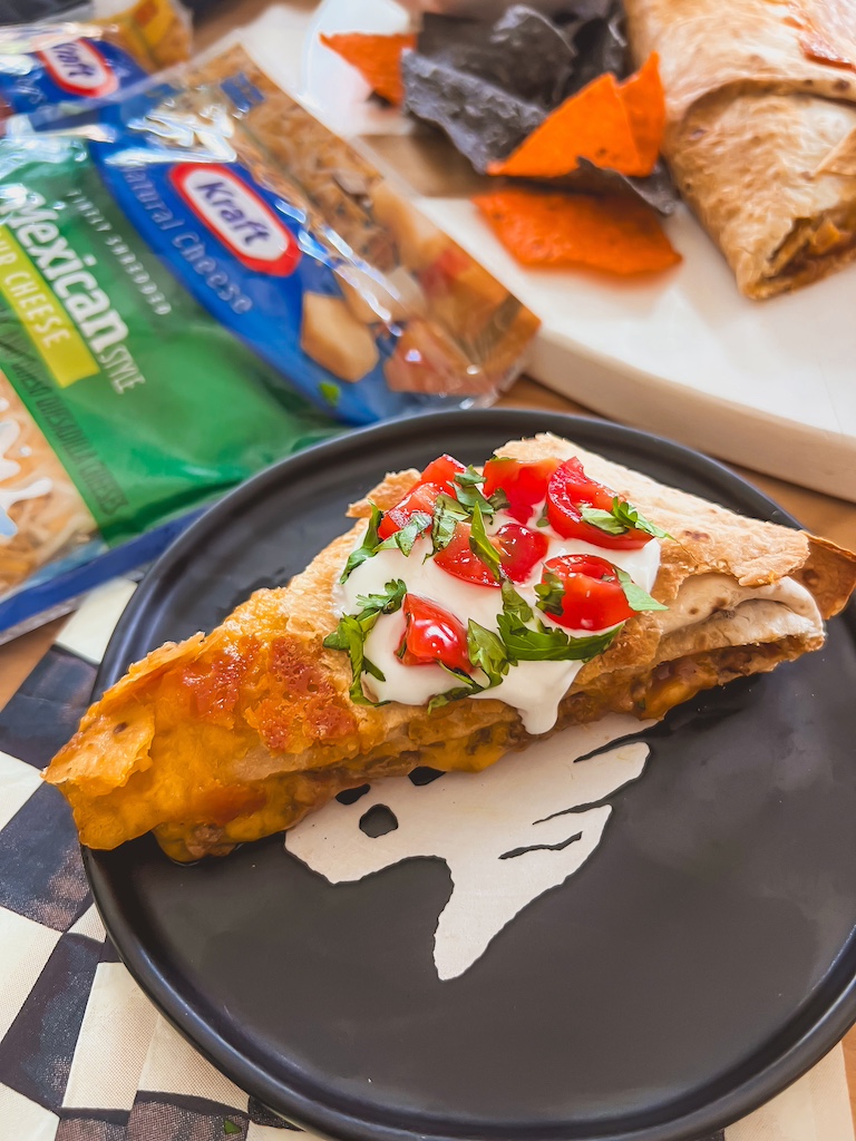 Slicing baked jack-o-lantern quesadilla like a pizza for easy serving.
