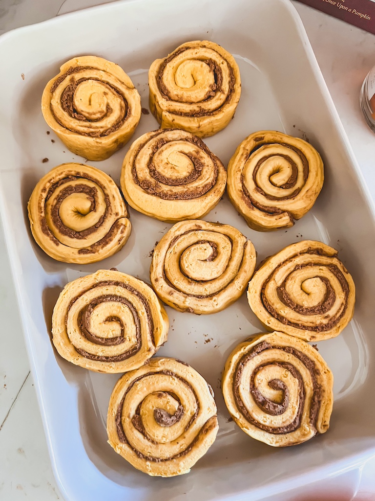 Unbaked Pillsbury Pumpkin Spice Grands arranged in a casserole dish before adding cream