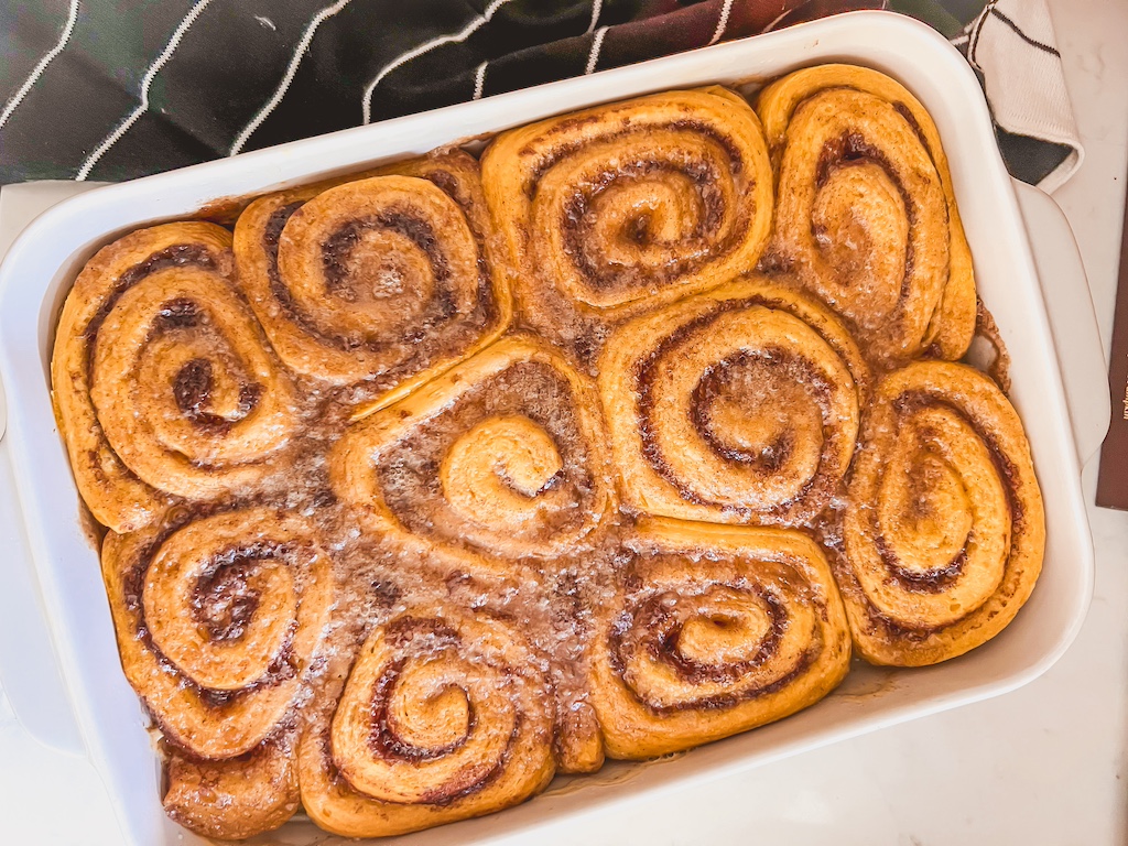 Freshly baked pumpkin rolls bubbling in caramelized brown sugar sauce — soft, gooey, and golden brown.