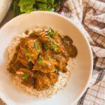 slow cooker butter chicken in a white bowl on top of rice