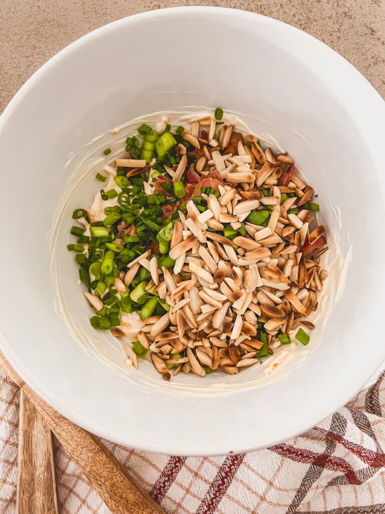 toasted almonds and green onions added to mayo and cheese in a white bowl