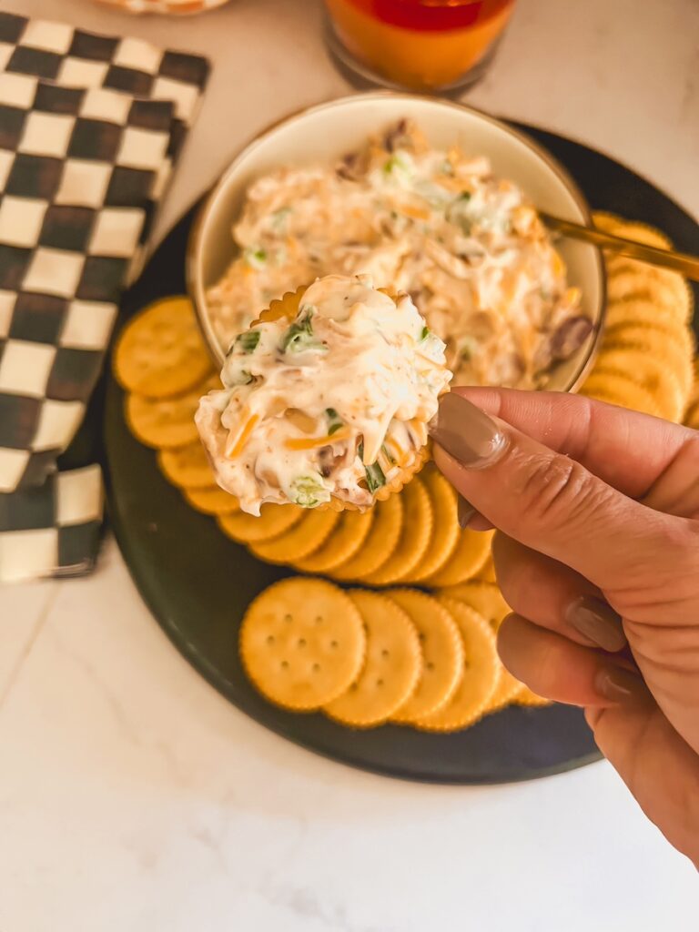 neiman marcus dip spread on a cracker with a hand holding it