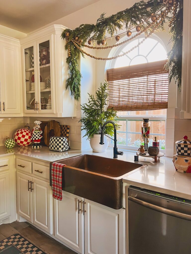 view of christmas kitchen sink with garland hanging above the window