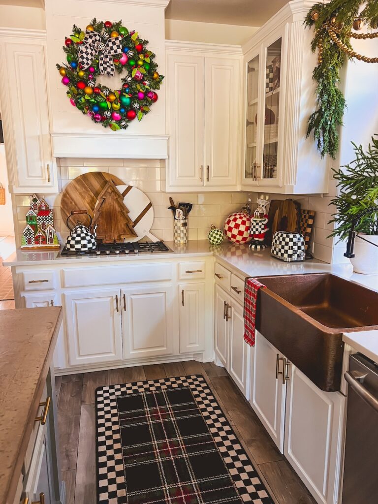 christmas kitchen with plaid rug, wreath above the stove and classic red and green with mackenzie childs