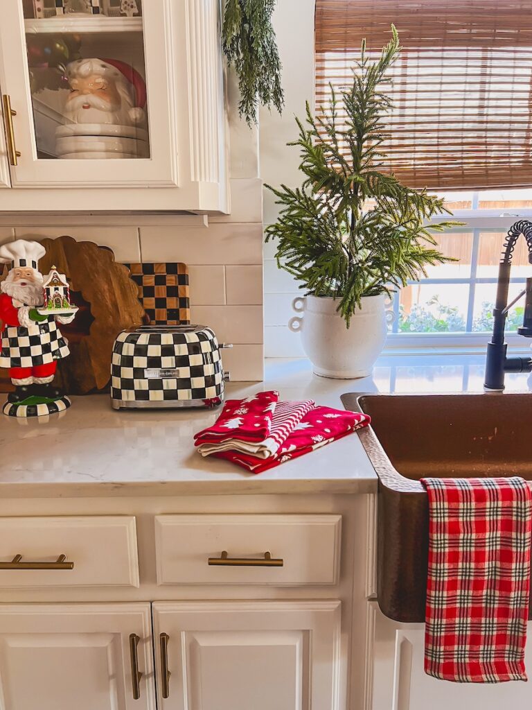 christmas kitchen with red plaid towels with norfolk tree next to the sink and a mackenzie childs toaster