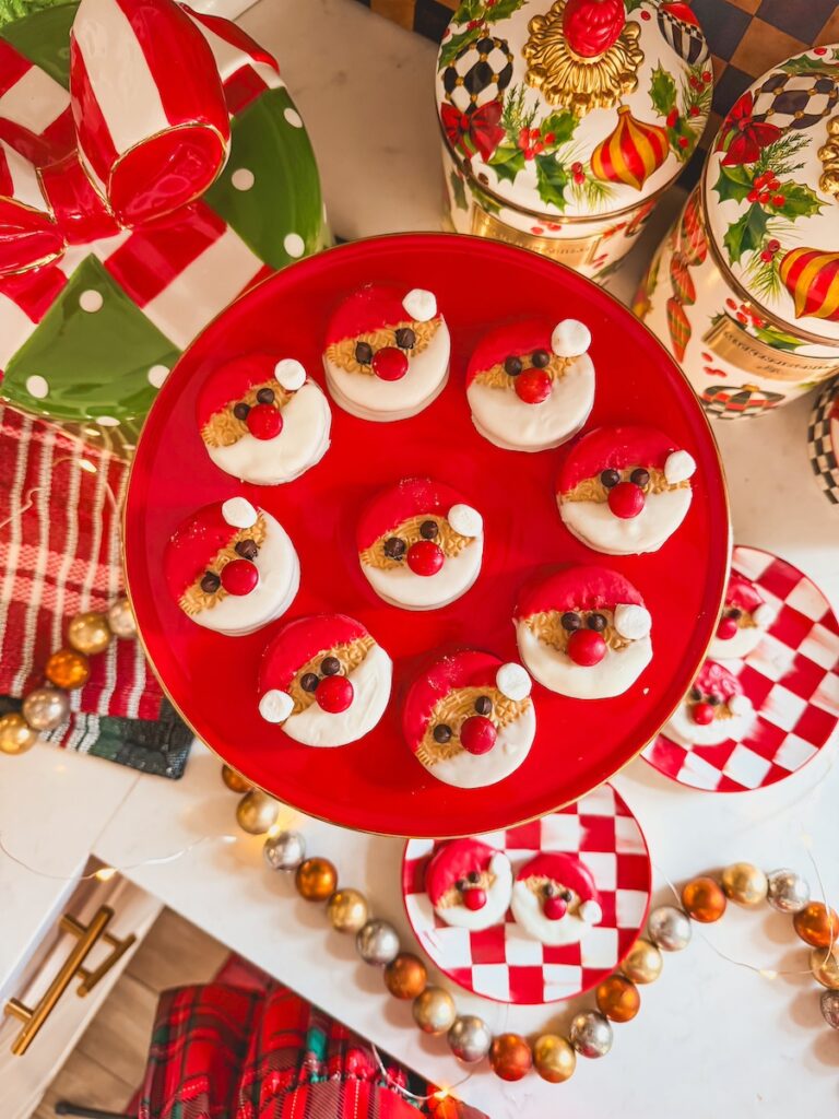 santa oreo cookies on a red cake stand with christmas decor 