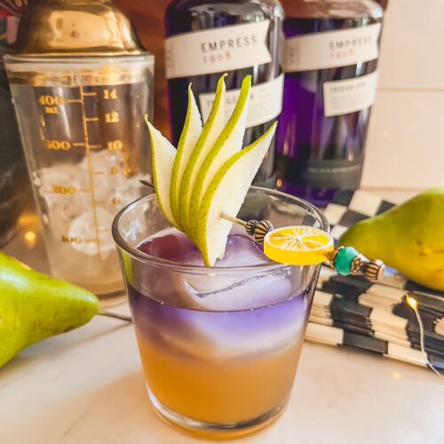 layered fall cocktail with empress gin, in a clear glass with pear garnish