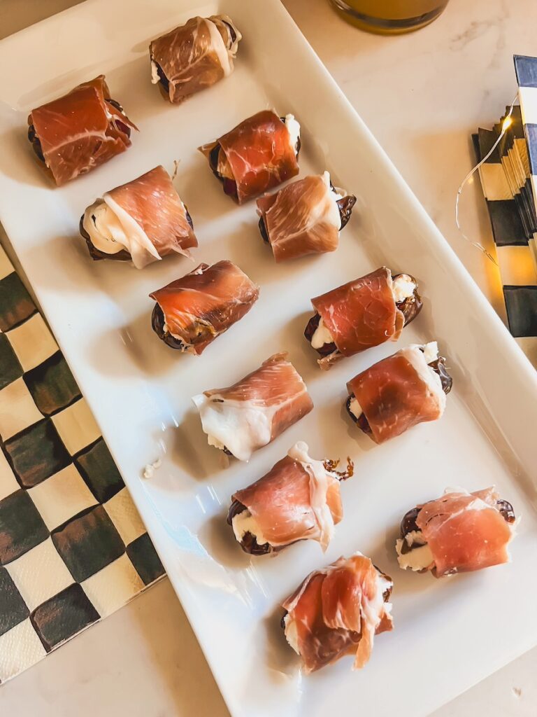 prosciutto wrapped dates on a white plate