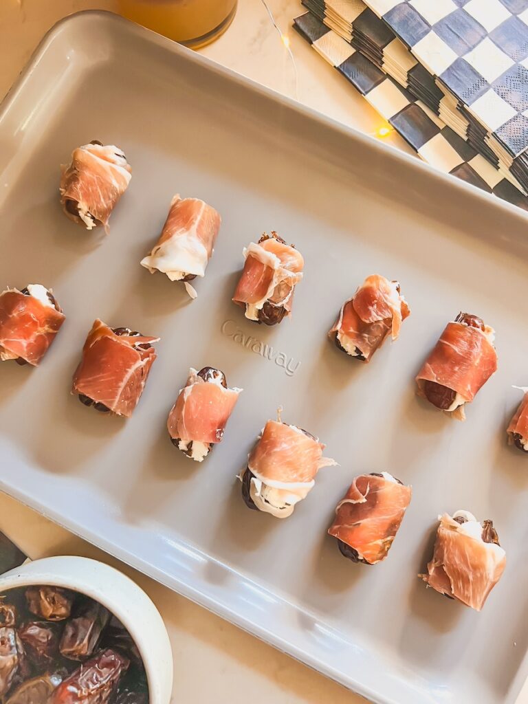 prosciutto wrapped dates on a baking sheet