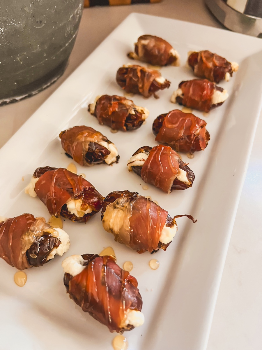 prosciutto wrapped dates on a white plate