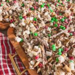 close up of christmas crack chex mix on wood board