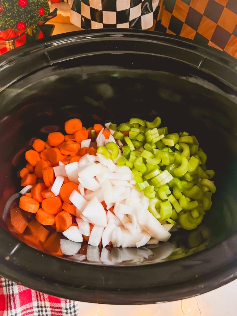 Some ingredients for slow cooker chicken noodle soup in a slow cooker bowl.