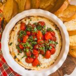 baked ricotta dip in a white dish with baguettes around the side