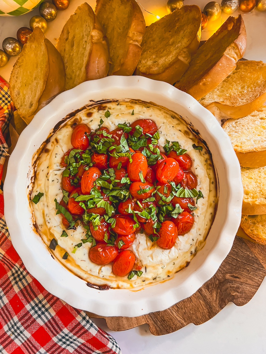 baked ricotta dip in a white dish with baguettes around the side