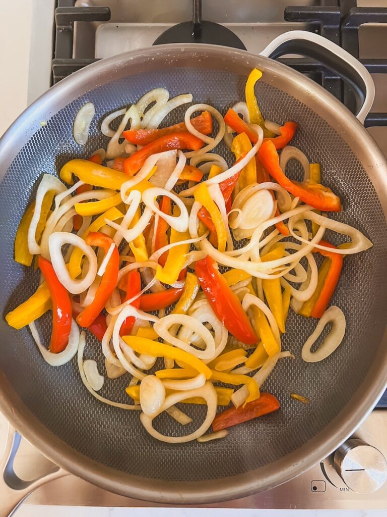 Skillet with peppers and onions cooking. 