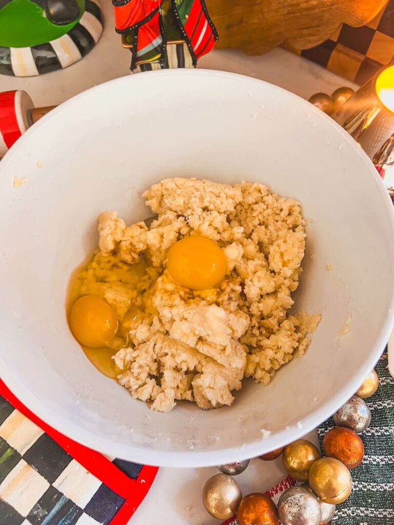 Eggs added to the creamed butter and sugar in a white bowl. 